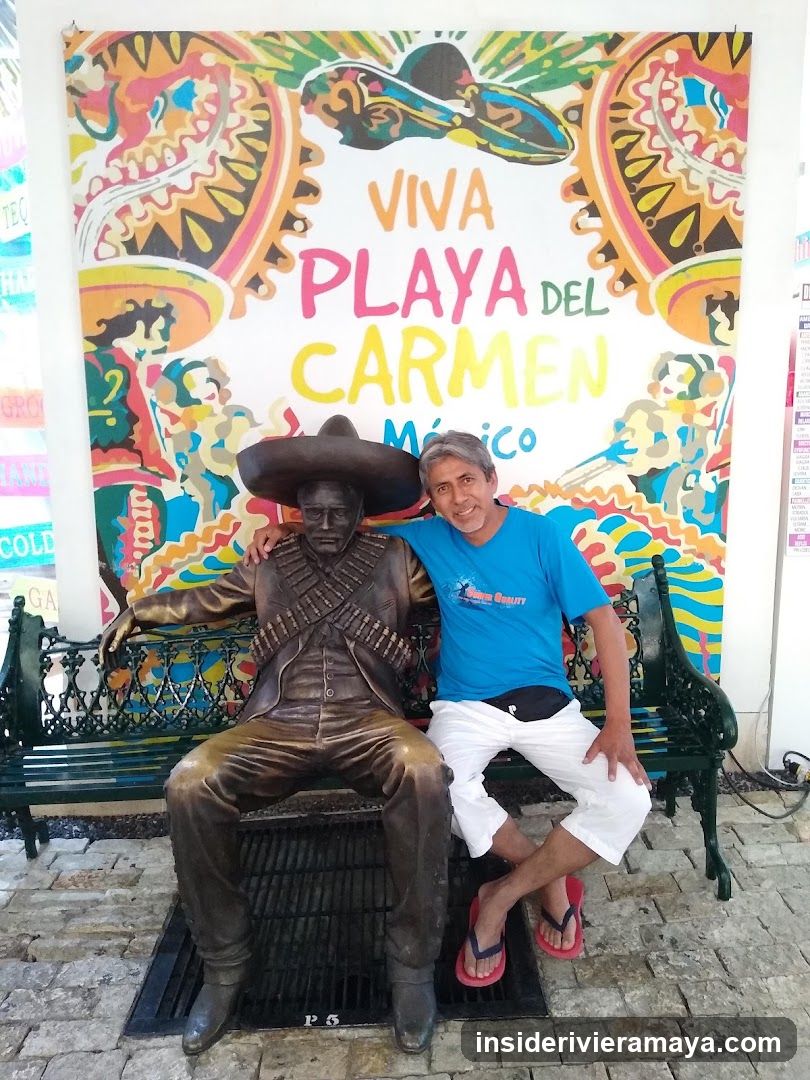 Man posing with statue in Playa del Carmen