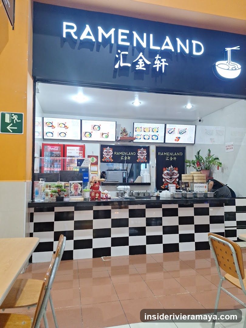 A storefront for a restaurant named Ramenland, featuring a large black sign with white lettering and Chinese characters. The counter has a black and white checkered pattern, and digital menu boards are visible above the service area.
