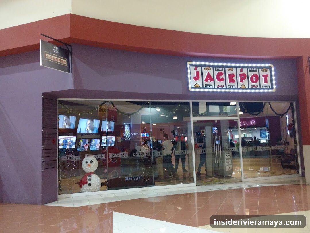 A storefront with purple walls and a red overhang. A large illuminated sign reads 'JACKPOT BAR' above glass doors. A snowman decoration stands in the window, and people are visible inside.