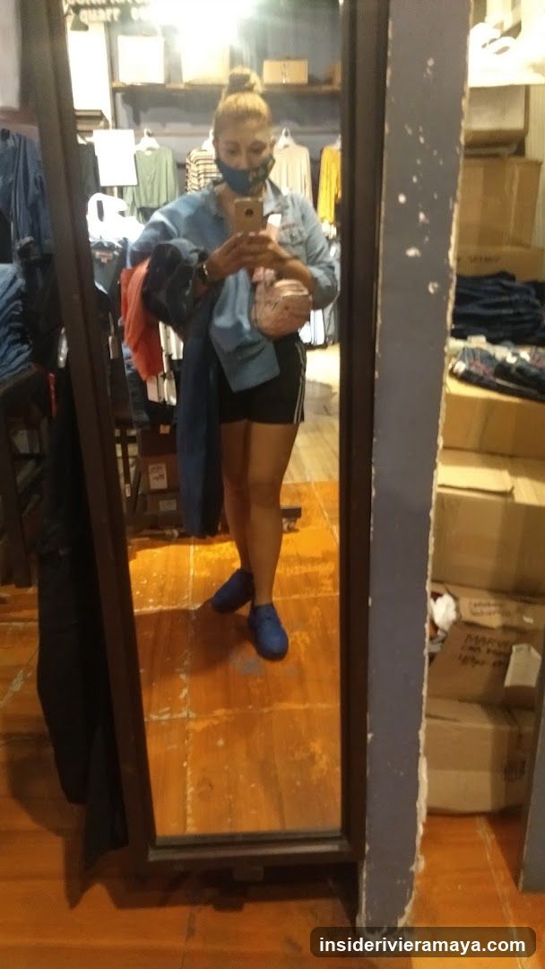 Woman taking a mirror selfie in a clothing store