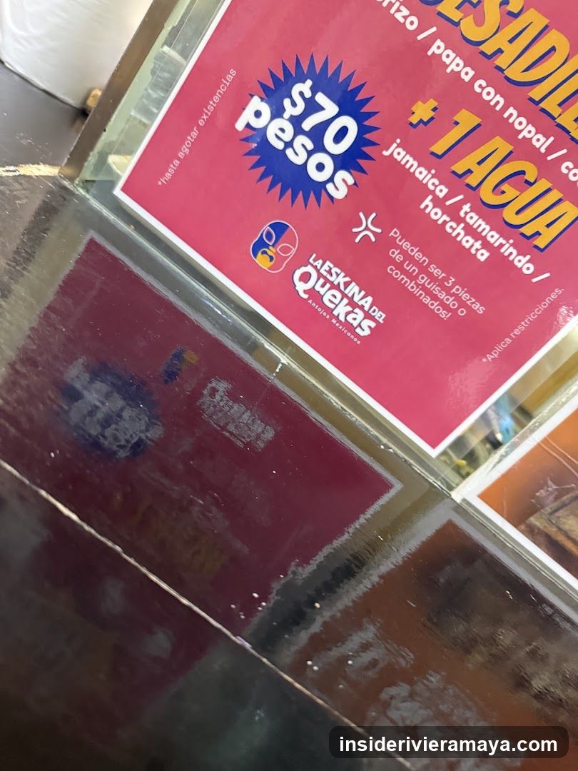 A close-up, angled shot of a red promotional sign taped to a glass surface. The sign advertises a deal for $70 pesos including one water, listing flavors like jamaica, tamarindo, and horchata. The logo for 'La Esquina del Queso' is visible at the bottom.