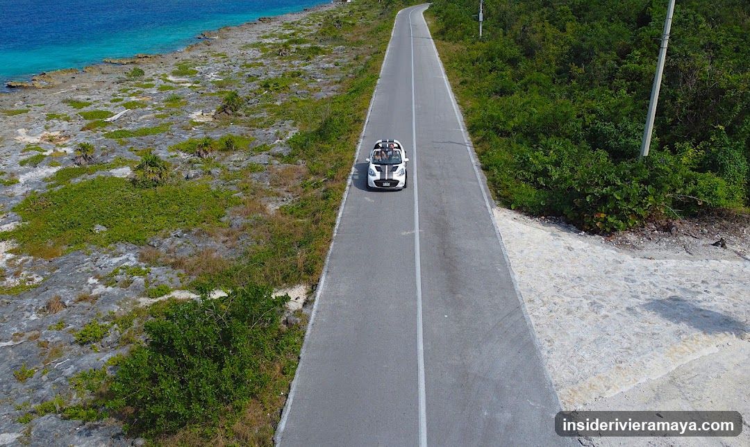 Aerial view of a convertible car on a coastal road