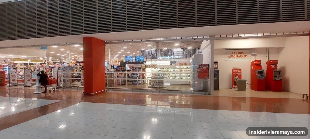 A wide shot of a commercial storefront inside a mall. The central store, labeled 'DERMA CENTER', features large glass windows and doors. To the right, a designated area for 'CAJEROS AUTOMATICOS' (ATMs) contains three red machines. To the left, aisles of a larger store are visible with a shopper pushing a cart. The floor is tiled and reflective.