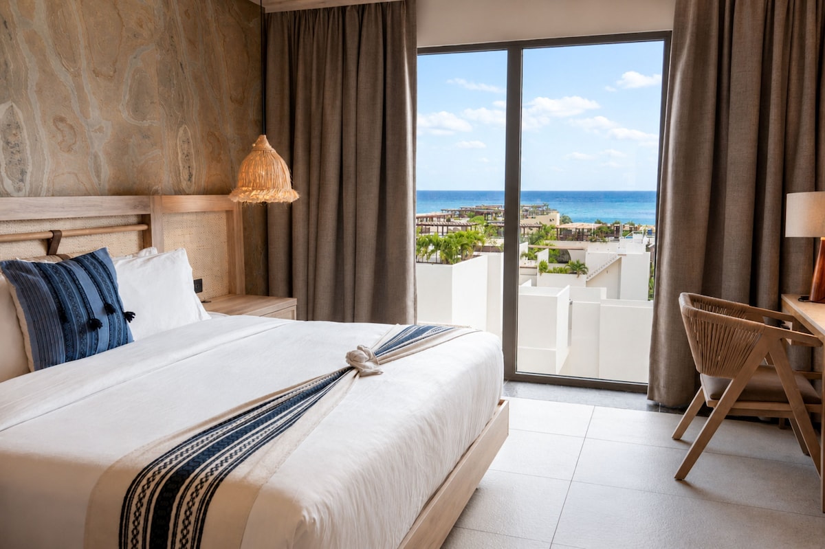 Hotel Indigo Playa del Carmen guest room with premium bedding, desk and ocean-view corner window